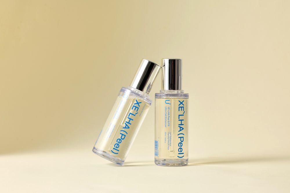 Two XE'LHA Peel bottles on a warm beige background